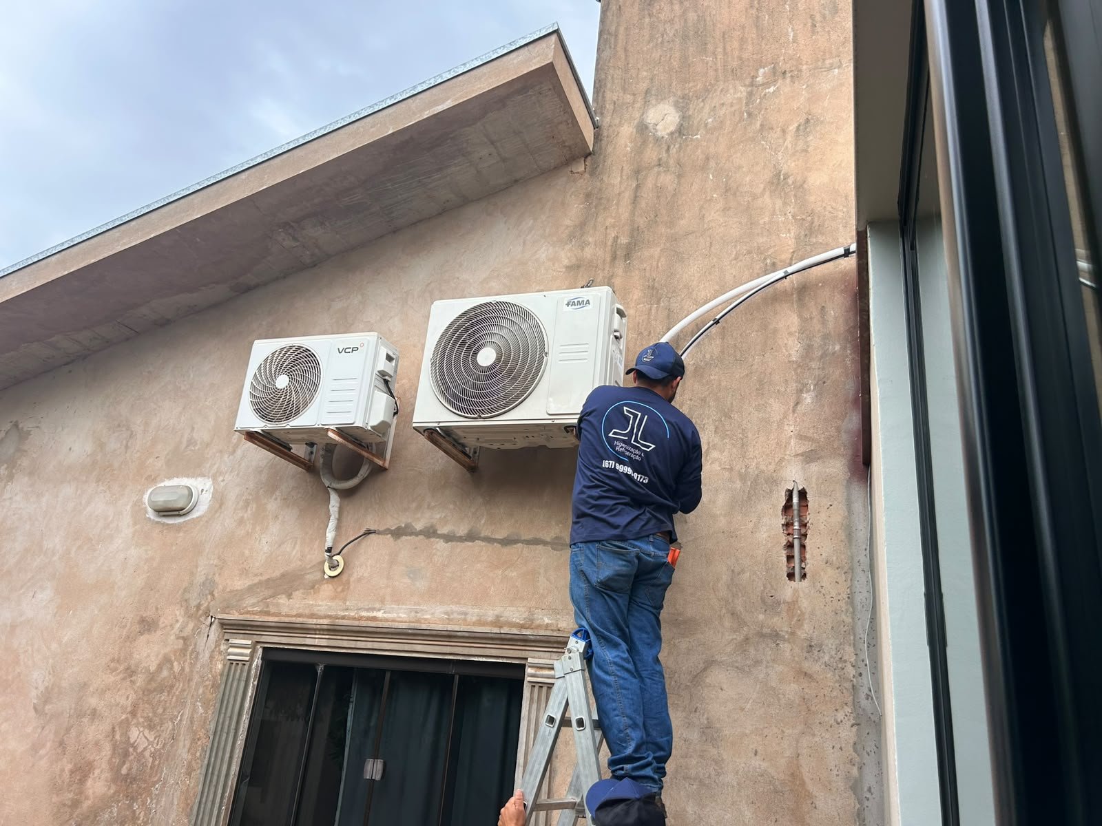 Técnico da JL instalando unidades condensadoras de ar-condicionado em fachada em Bela Vista-MS